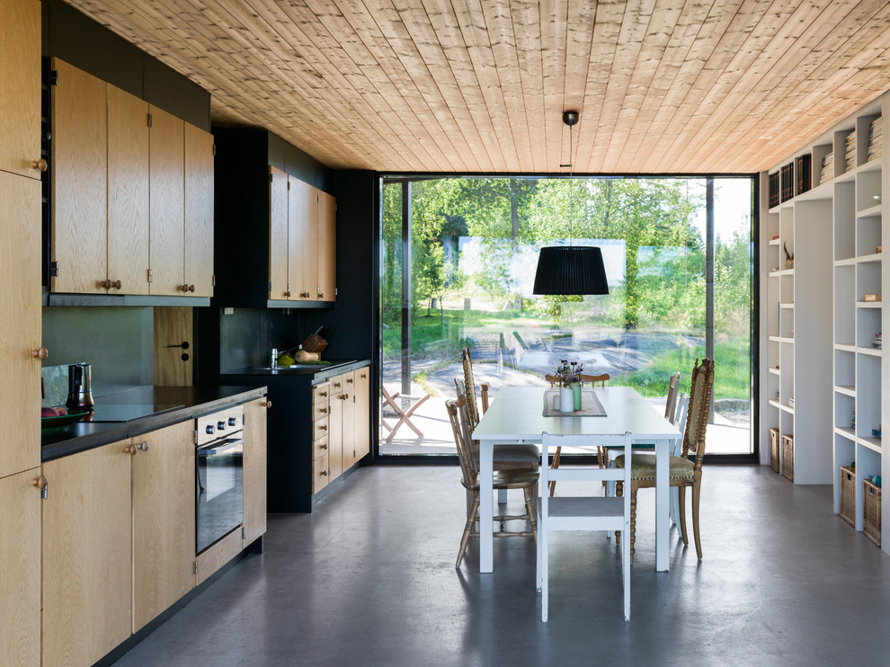 Idee per una sala da pranzo aperta verso la cucina nordica di medie dimensioni con pavimento in cemento, pavimento grigio e pareti nere