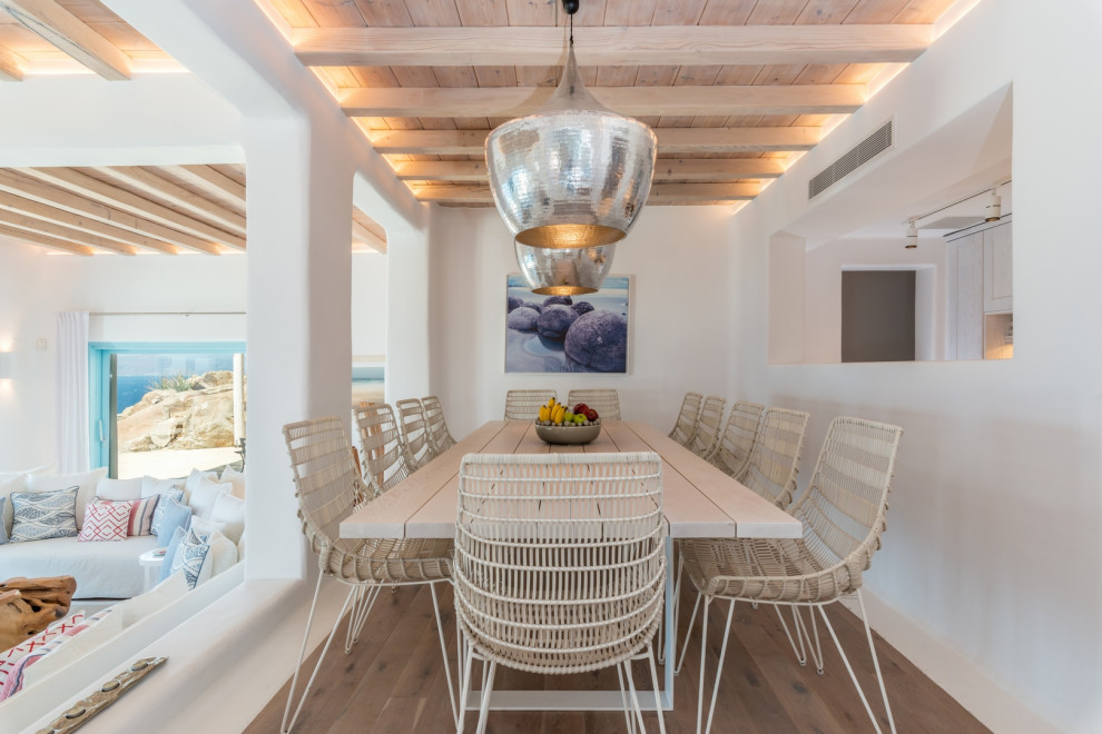 Esempio di una sala da pranzo stile marino con pareti bianche, pavimento in legno massello medio, pavimento marrone, travi a vista e soffitto in legno