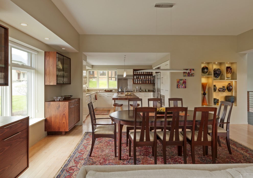 Ispirazione per una sala da pranzo aperta verso la cucina moderna di medie dimensioni con pareti beige e parquet chiaro
