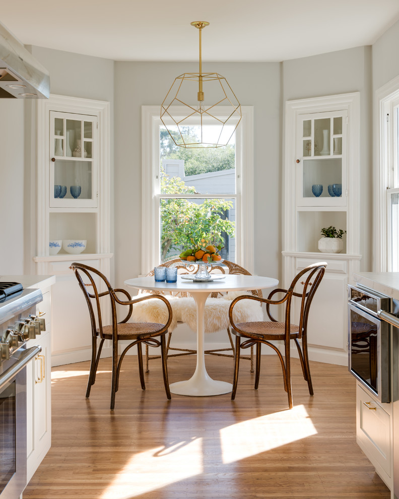 This is an example of a classic kitchen/dining room in San Francisco with grey walls and light hardwood flooring.