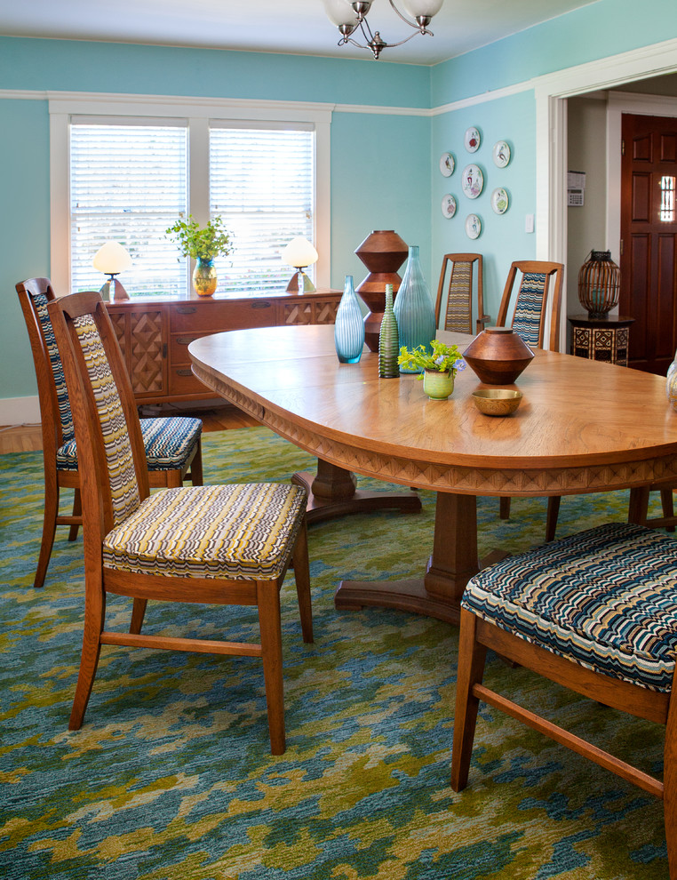 Cette image montre une salle à manger vintage fermée et de taille moyenne avec un mur bleu, un sol en bois brun et aucune cheminée.