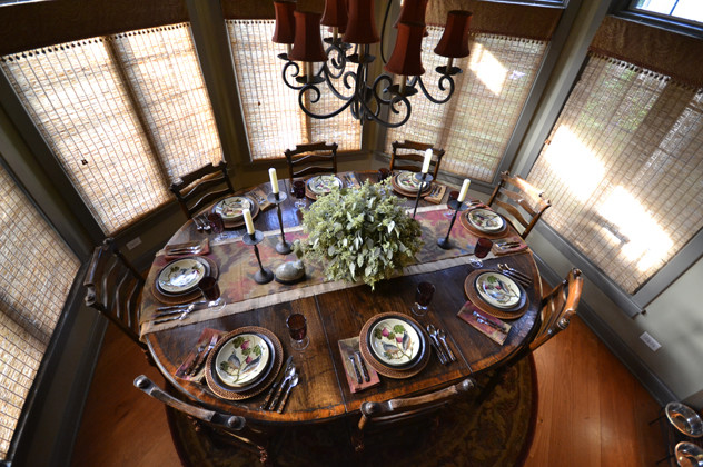 Cette image montre une salle à manger ouverte sur le salon chalet de taille moyenne avec un mur vert, un sol en bois brun et aucune cheminée.