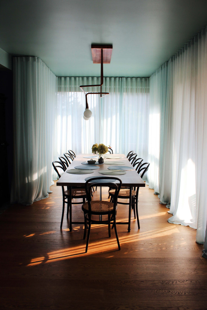 Cette photo montre une salle à manger ouverte sur la cuisine éclectique de taille moyenne avec un mur vert, parquet clair, une cheminée standard, un manteau de cheminée en plâtre et un sol marron.