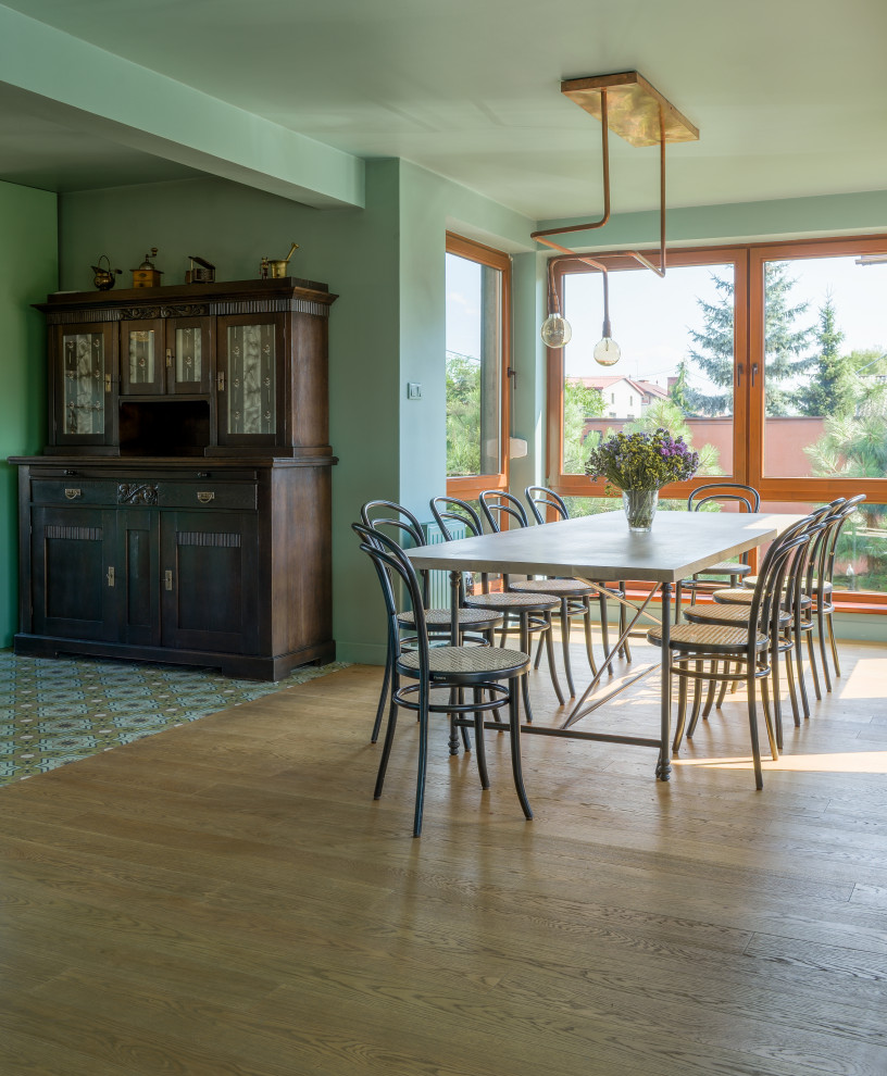 Пример оригинального дизайна: кухня-столовая среднего размера в стиле фьюжн с зелеными стенами, светлым паркетным полом, стандартным камином, фасадом камина из штукатурки и коричневым полом