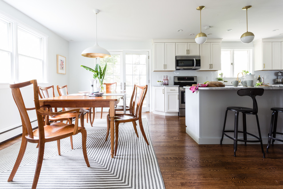 Idée de décoration pour une petite salle à manger ouverte sur la cuisine minimaliste avec un mur gris, un sol en bois brun, une cheminée standard, un manteau de cheminée en métal et un sol marron.