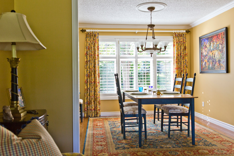 Foto de comedor clásico pequeño cerrado con paredes amarillas y suelo de madera en tonos medios