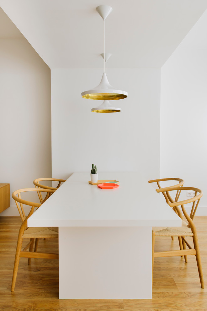 Cette photo montre une salle à manger ouverte sur la cuisine tendance de taille moyenne avec un mur blanc, un sol en bois brun et aucune cheminée.