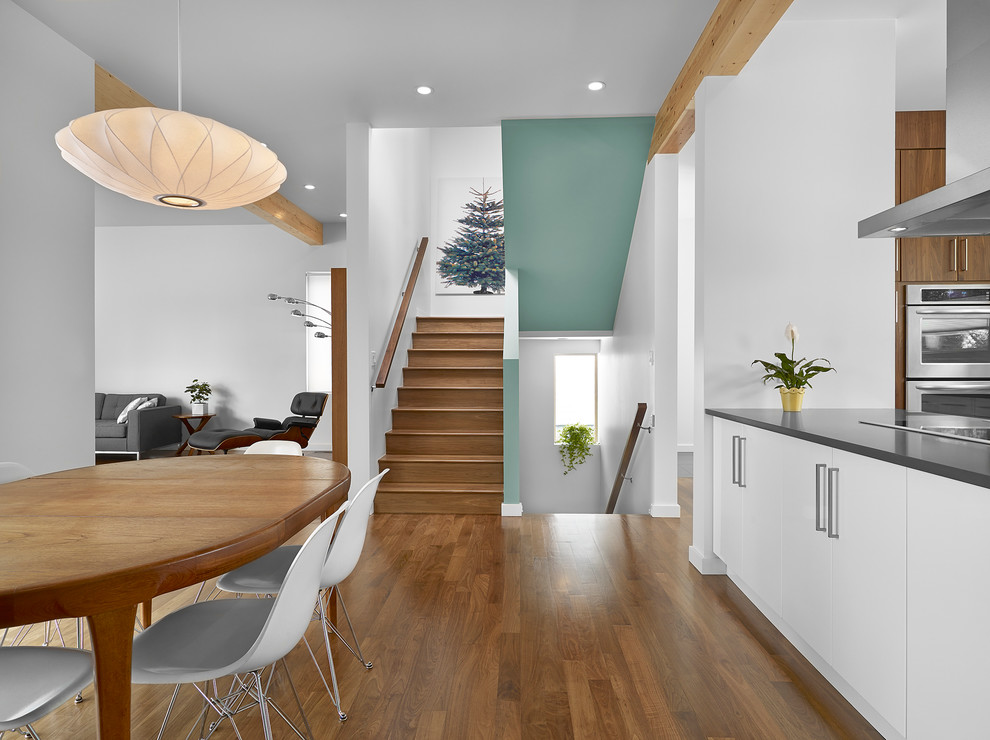 Immagine di una sala da pranzo aperta verso il soggiorno moderna di medie dimensioni con pareti bianche, pavimento in legno massello medio, nessun camino e pavimento marrone