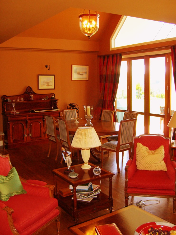 Offenes, Großes Klassisches Esszimmer mit oranger Wandfarbe und dunklem Holzboden in Sonstige