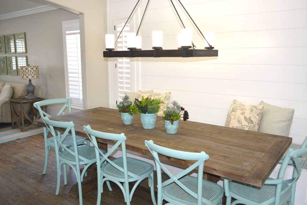 Cette image montre une salle à manger ouverte sur la cuisine marine de taille moyenne avec un mur blanc, parquet foncé et un sol marron.