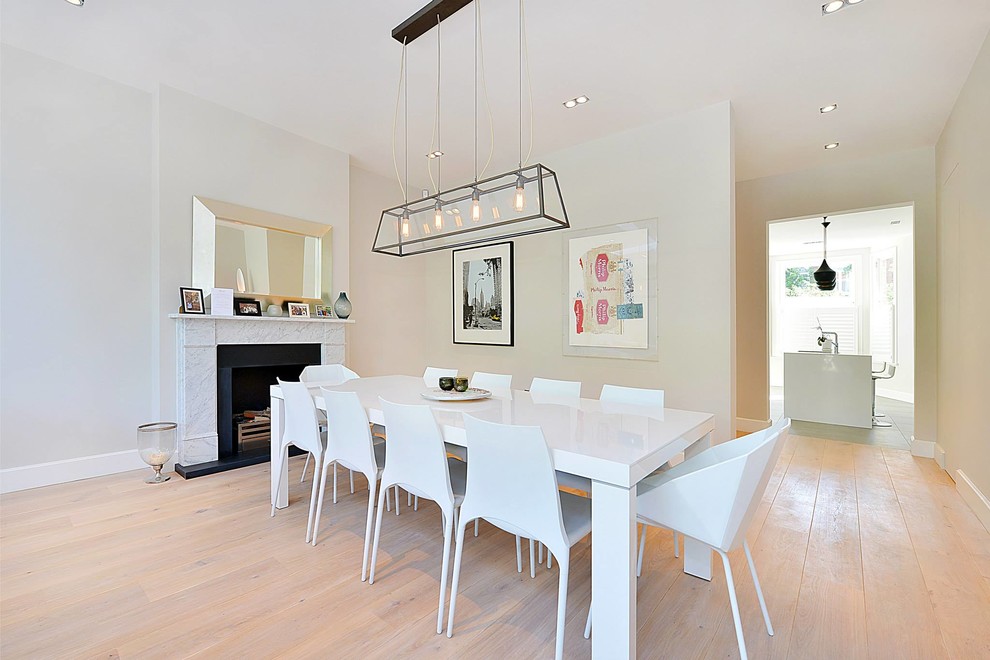 Exemple d'une salle à manger tendance de taille moyenne avec un mur beige, parquet clair et une cheminée standard.