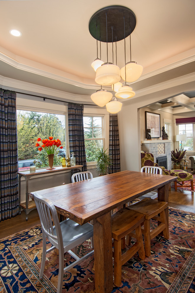 Exemple d'une salle à manger craftsman de taille moyenne avec un sol en bois brun, une cheminée standard, un manteau de cheminée en carrelage, un sol marron et éclairage.