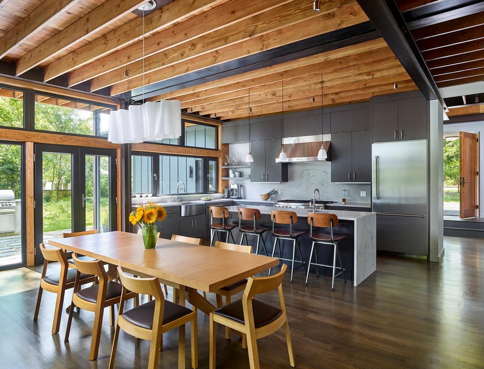 Immagine di una grande sala da pranzo aperta verso la cucina minimal con pavimento marrone e parquet scuro
