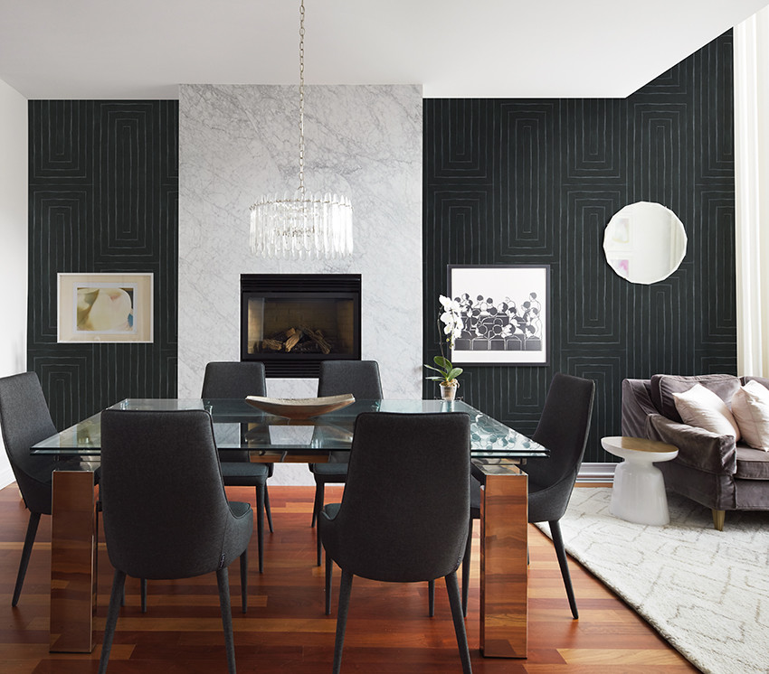 Foto di una sala da pranzo aperta verso il soggiorno design con pareti nere, parquet scuro, camino classico, cornice del camino in pietra e pavimento marrone