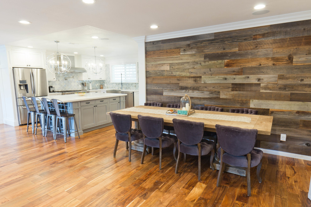 Immagine di una grande sala da pranzo aperta verso la cucina chic con pareti grigie, parquet chiaro, stufa a legna e cornice del camino piastrellata