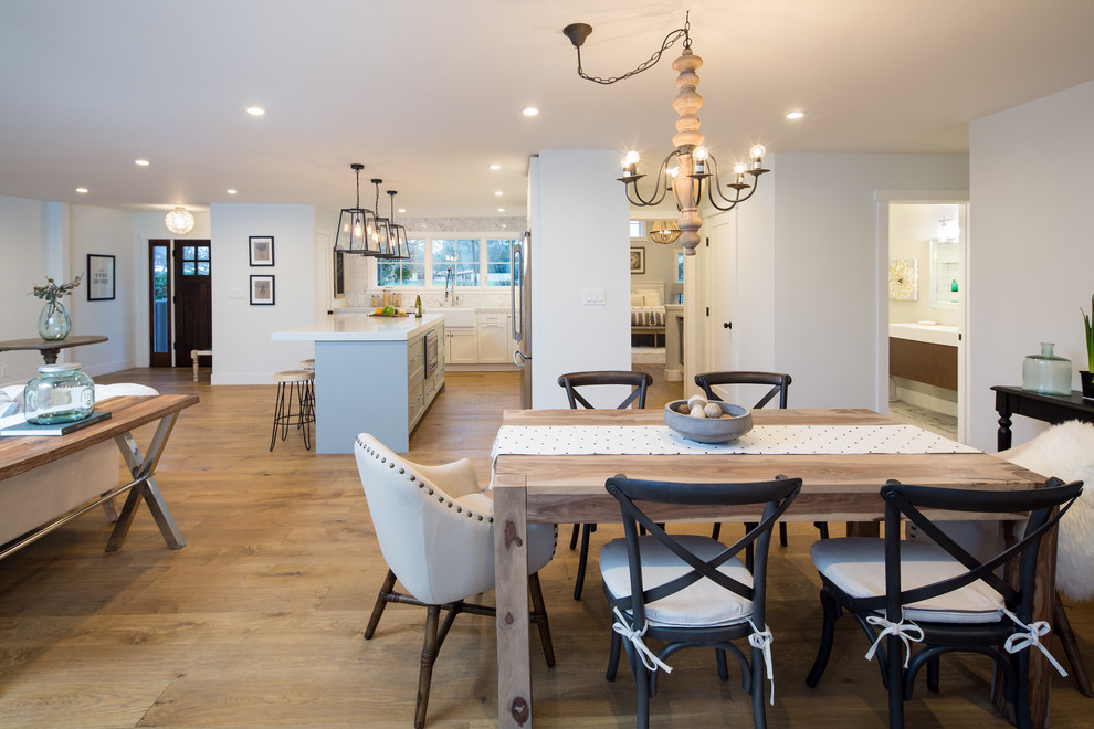 Cette photo montre une salle à manger ouverte sur le salon nature de taille moyenne avec un mur blanc, un sol en bois brun, une cheminée standard, un manteau de cheminée en brique et un sol marron.