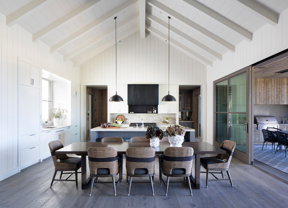 Cette photo montre une salle à manger ouverte sur le salon nature avec un mur blanc, parquet foncé, un sol marron, un plafond voûté et du lambris de bois.