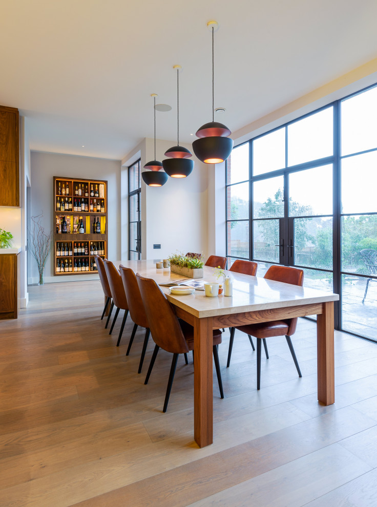 Immagine di una grande sala da pranzo aperta verso la cucina minimal con pavimento in legno massello medio, pareti bianche e pavimento beige