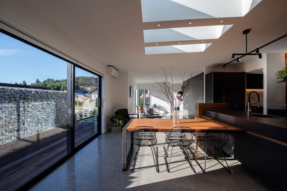 Ispirazione per una grande sala da pranzo aperta verso la cucina minimalista con pareti multicolore, pavimento in cemento e pavimento grigio