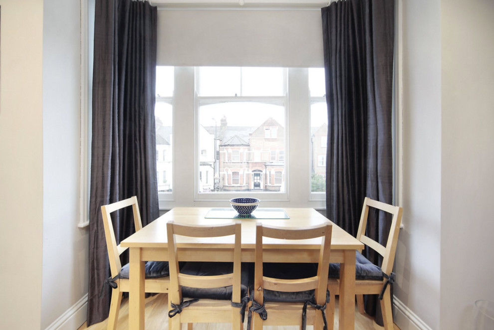 This is an example of a small modern open plan dining room in London with grey walls.