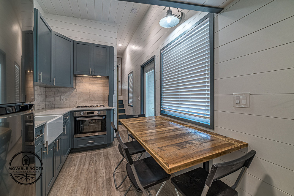 Cette image montre une petite salle à manger ouverte sur la cuisine minimaliste avec un mur blanc, un sol en vinyl, aucune cheminée et un sol beige.