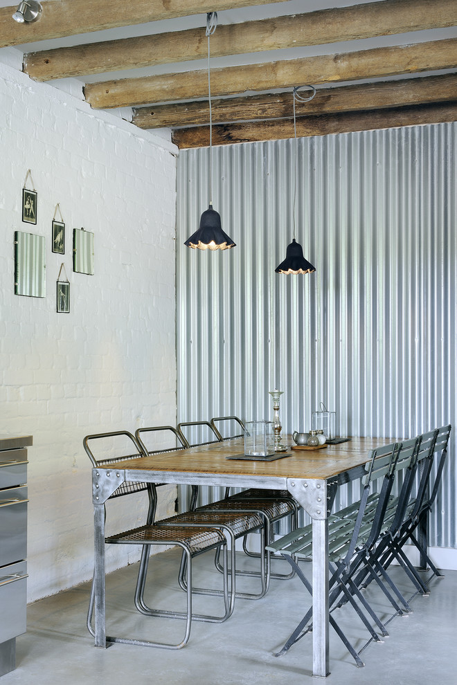 Cette image montre une salle à manger urbaine avec un mur blanc et sol en béton ciré.