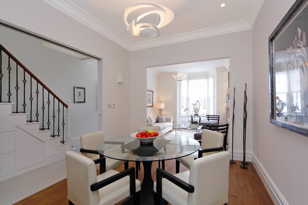 This is an example of a medium sized contemporary dining room in London with white walls, medium hardwood flooring and no fireplace.