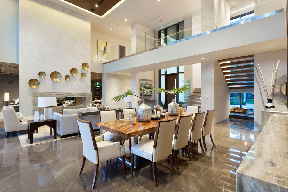 На фото: большая гостиная-столовая в стиле модернизм с бежевыми стенами, мраморным полом, горизонтальным камином и фасадом камина из камня с