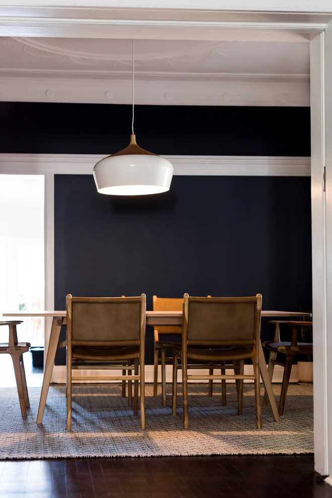 Modern inredning av en mellanstor separat matplats, med blå väggar, mörkt trägolv och svart golv