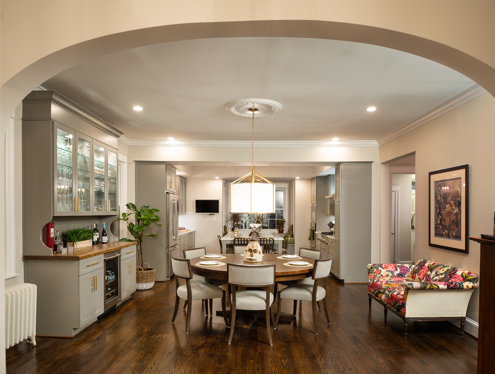 Immagine di una grande sala da pranzo aperta verso la cucina classica con pareti beige e parquet scuro