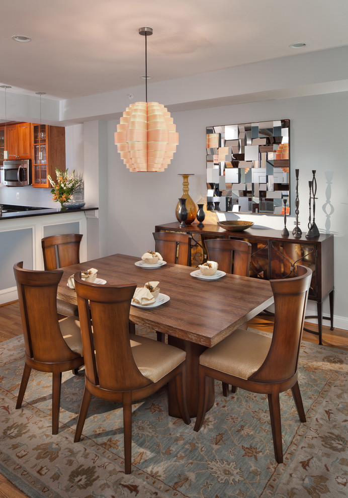 Idée de décoration pour une salle à manger ouverte sur la cuisine design avec un mur gris et un sol en bois brun.