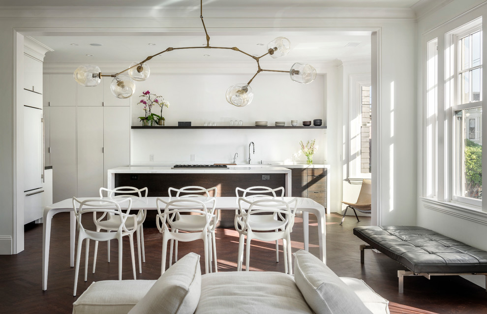 Immagine di una sala da pranzo aperta verso il soggiorno minimal con pareti bianche e parquet scuro