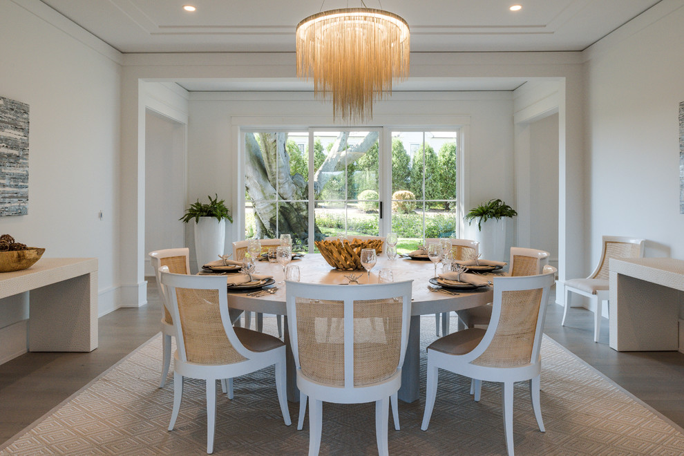 Foto di una sala da pranzo aperta verso il soggiorno costiera con pareti bianche, parquet scuro e pavimento marrone
