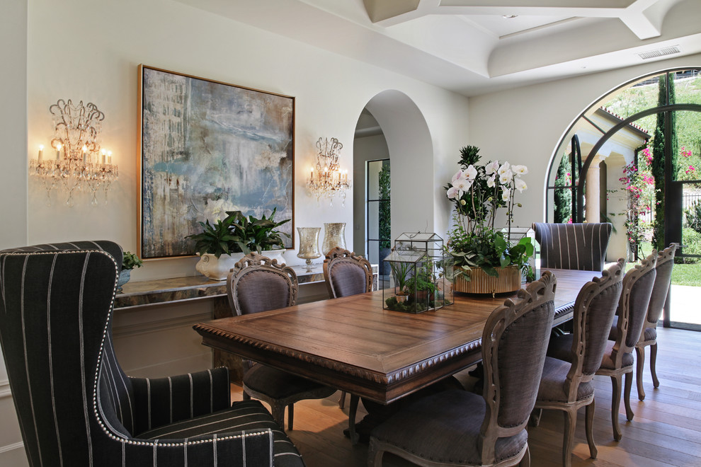 Cette photo montre une salle à manger méditerranéenne avec un mur blanc et un sol en bois brun.
