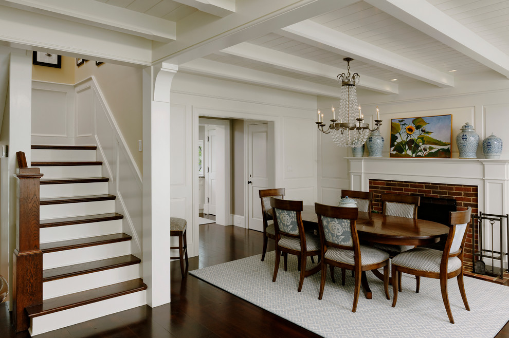 Exemple d'une grande salle à manger ouverte sur le salon chic avec un mur blanc, parquet foncé, une cheminée standard et un manteau de cheminée en brique.