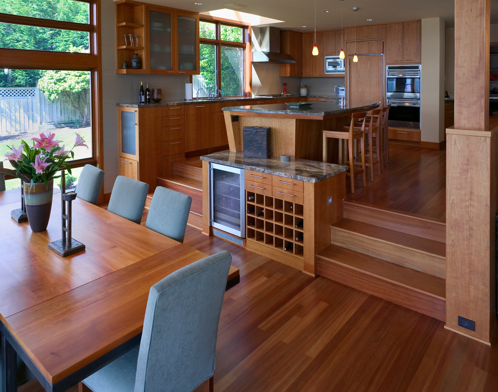 На фото: кухня-столовая в современном стиле с паркетным полом среднего тона без камина с