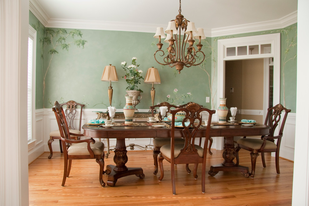 Inspiration pour une salle à manger traditionnelle fermée avec un mur vert, un sol en bois brun et éclairage.