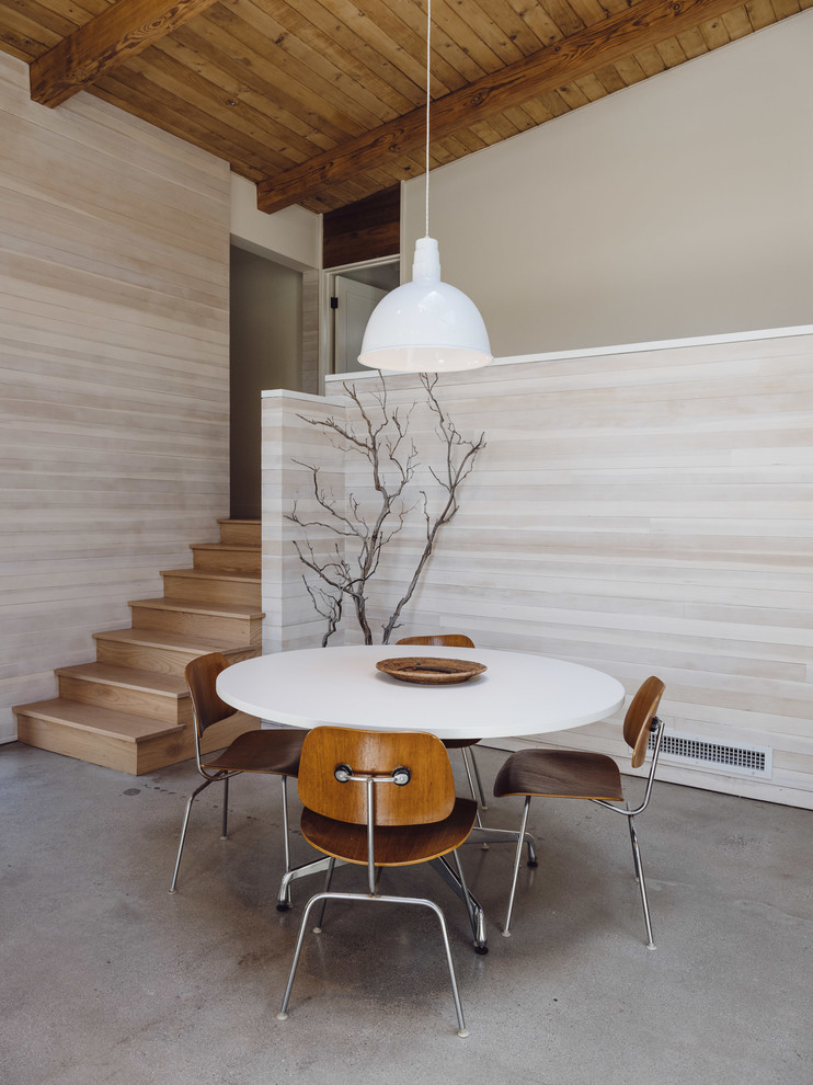 Idee per una sala da pranzo aperta verso il soggiorno minimalista di medie dimensioni con pareti bianche, pavimento in cemento, pavimento grigio e nessun camino