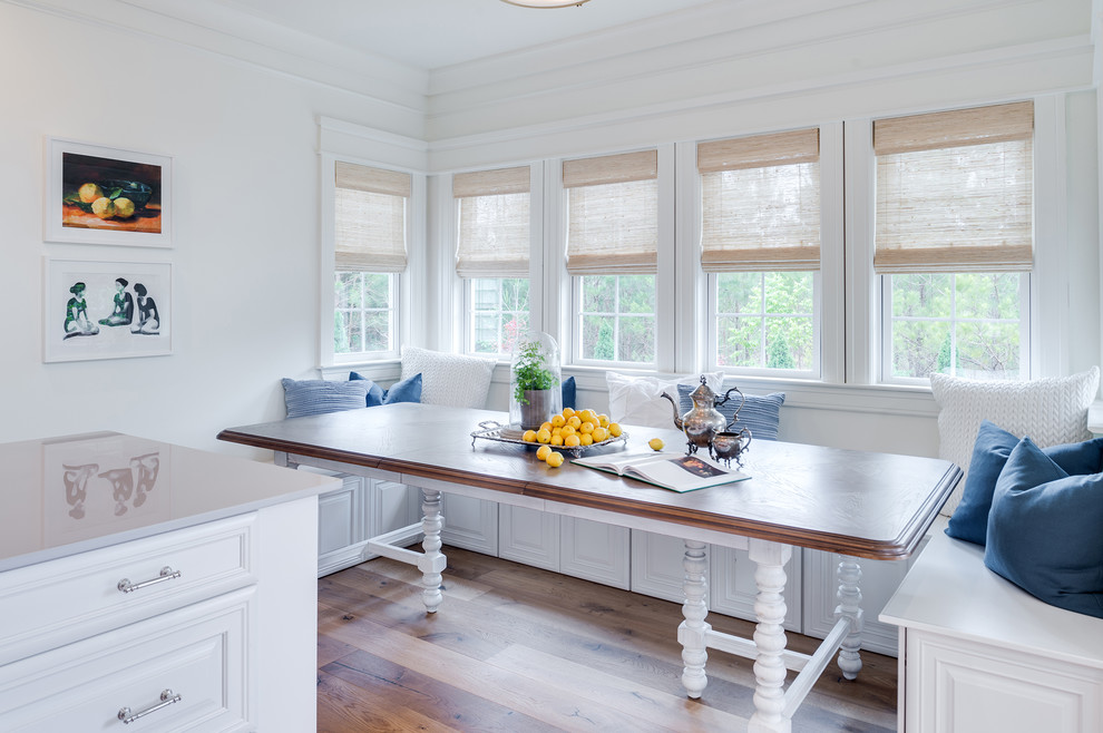 Immagine di una sala da pranzo aperta verso la cucina stile marino con pareti bianche, parquet chiaro e nessun camino