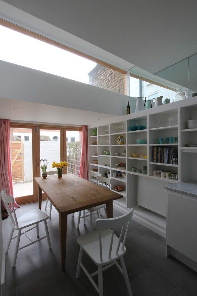 Inspiration pour une salle à manger ouverte sur la cuisine design avec un mur blanc et un sol en carrelage de porcelaine.