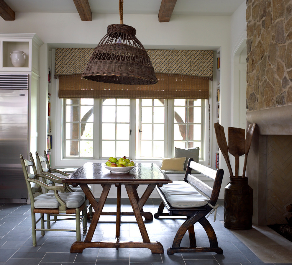 Diseño de comedor de cocina de estilo de casa de campo grande con paredes blancas, todas las chimeneas y marco de chimenea de piedra