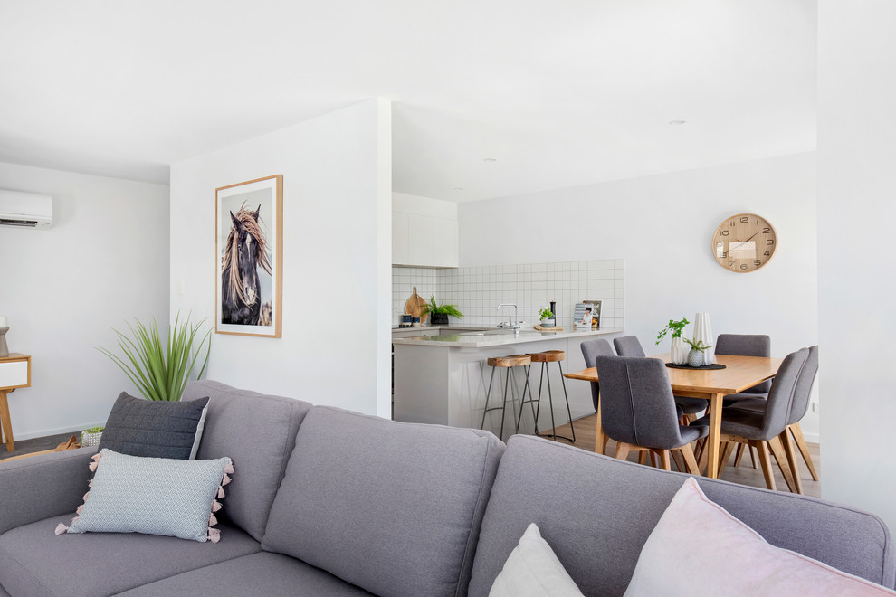 Immagine di una piccola sala da pranzo aperta verso il soggiorno minimal con pareti bianche, pavimento in vinile e pavimento marrone