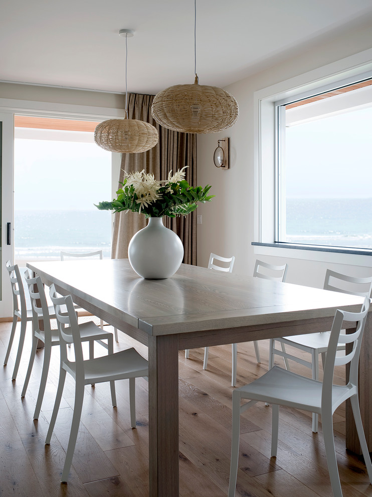 Cette image montre une salle à manger ouverte sur le salon marine avec un mur blanc et parquet clair.