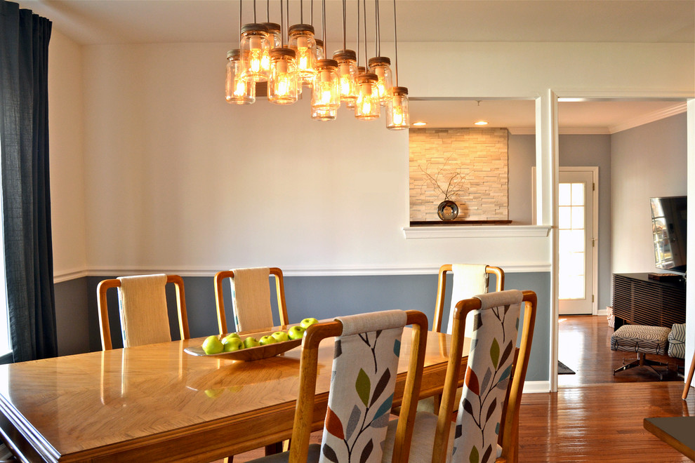 Aménagement d'une salle à manger ouverte sur la cuisine contemporaine de taille moyenne avec un mur gris, un sol en bois brun, une cheminée standard, un manteau de cheminée en pierre et un sol marron.