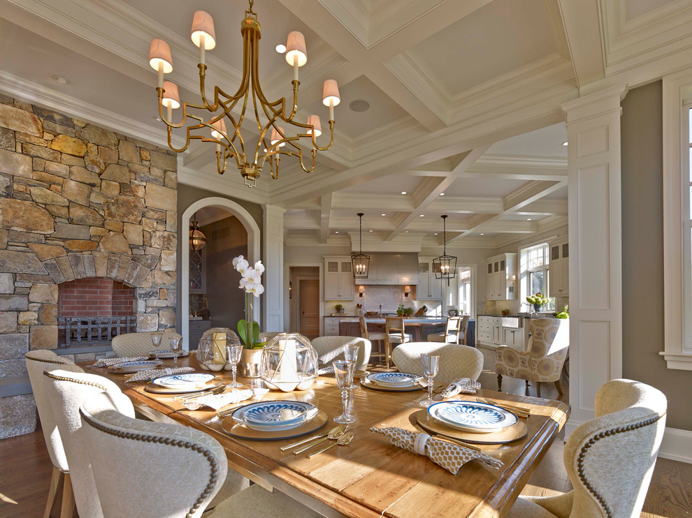 На фото: кухня-столовая в классическом стиле с серыми стенами, паркетным полом среднего тона, стандартным камином, фасадом камина из камня и коричневым полом с