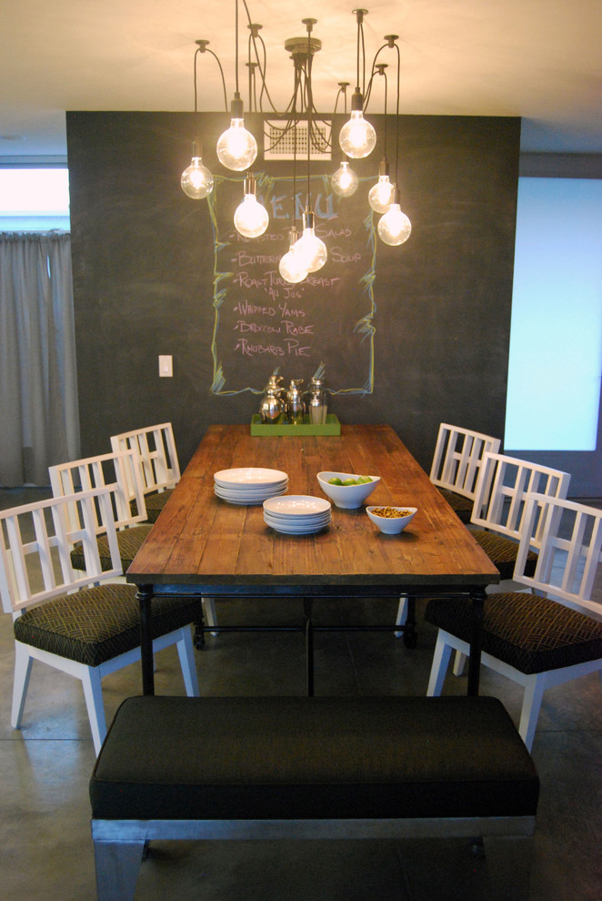 Ispirazione per una sala da pranzo aperta verso la cucina moderna di medie dimensioni con pareti nere e pavimento in cemento