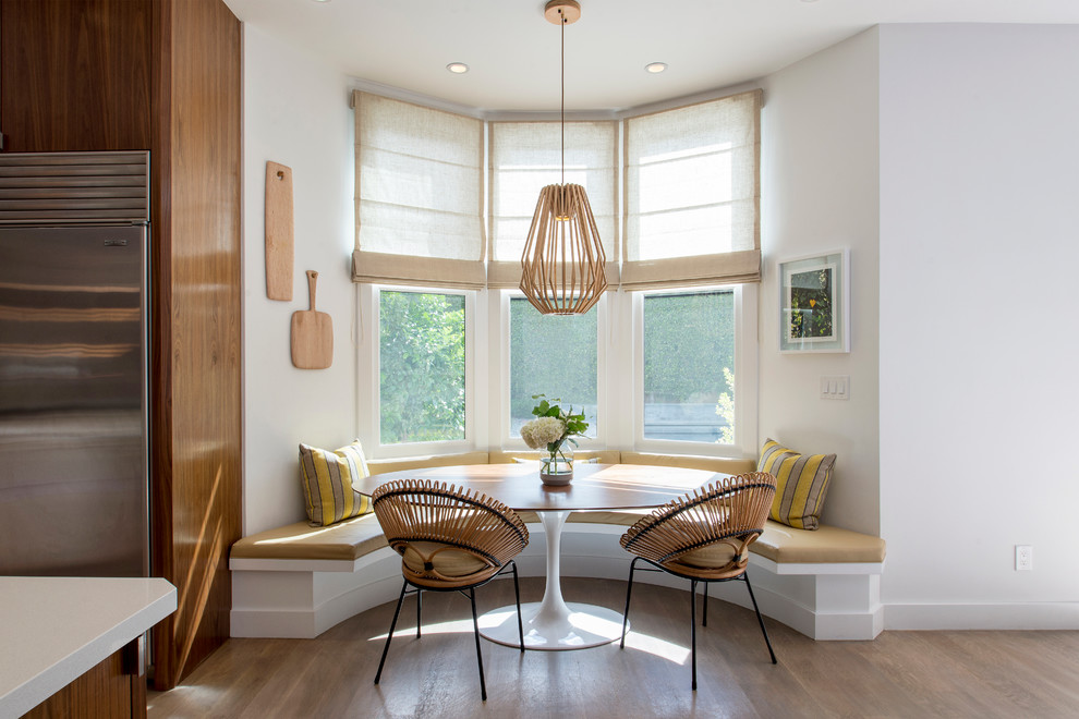 Immagine di una sala da pranzo aperta verso la cucina chic con pareti bianche e parquet chiaro