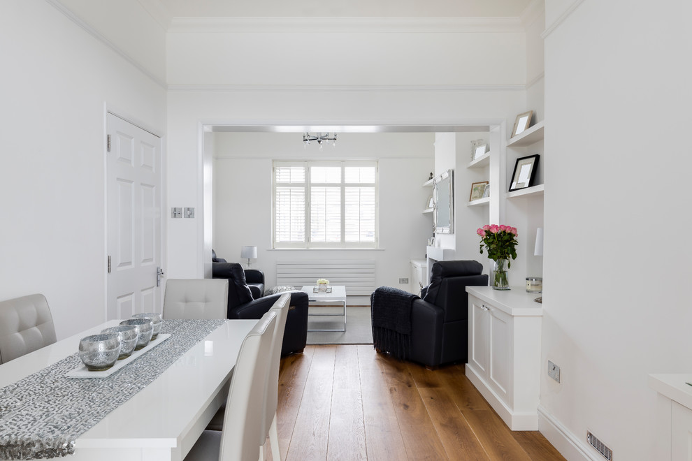 Offenes, Kleines Modernes Esszimmer mit weißer Wandfarbe, braunem Holzboden, Kamin, verputzter Kaminumrandung und braunem Boden in London