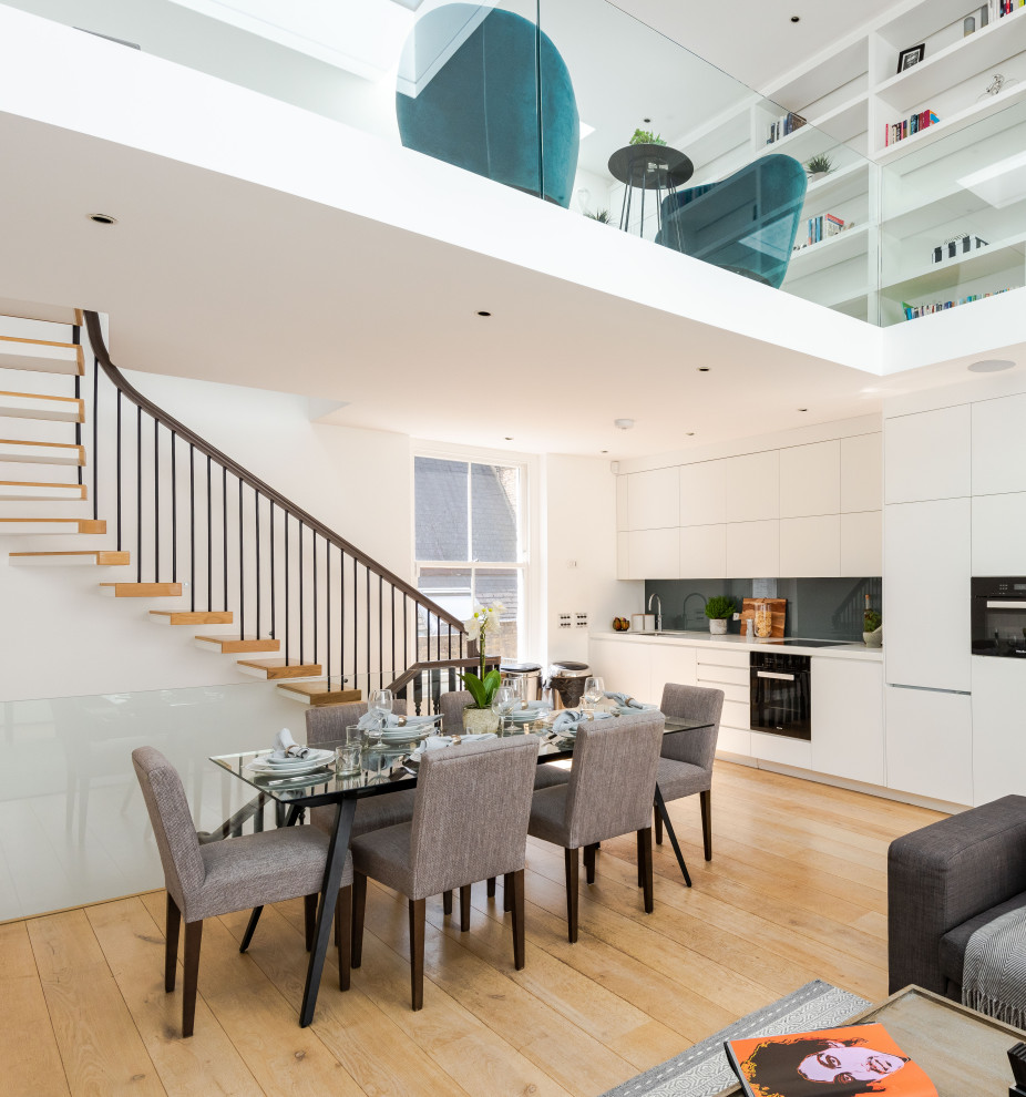 Photo of a contemporary kitchen/dining room in London with white walls, medium hardwood flooring, no fireplace and brown floors.