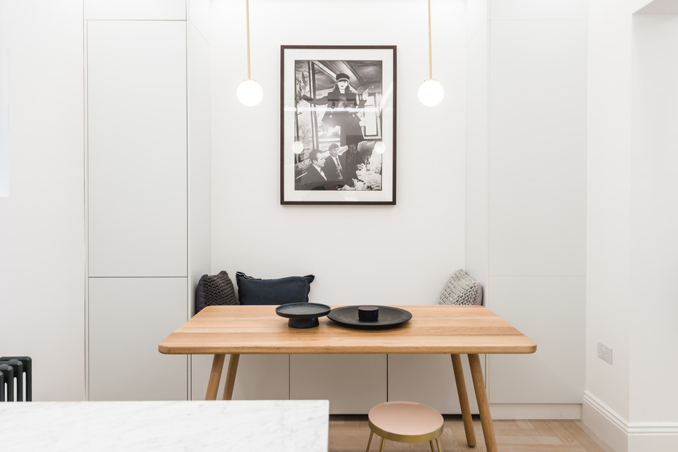 Immagine di una piccola sala da pranzo aperta verso la cucina scandinava con pareti bianche, parquet chiaro e pavimento beige